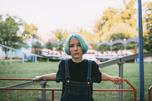 Portrait of teenage girl standing by railing at amusement park - FSIF01124