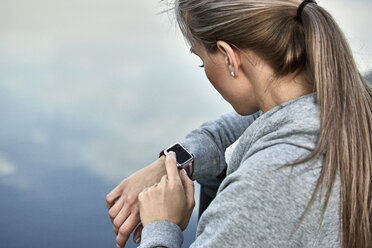 High angle view of woman using smart watch against lake - FSIF01160