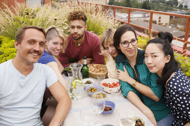 Porträt von glücklichen männlichen und weiblichen Freunden, die an einem Tisch im Freien auf einer Terrasse sitzen - FSIF01181