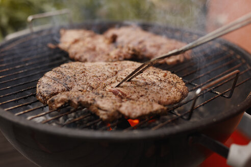 Nahaufnahme eines Steaks, das auf einem Grill im Innenhof gegrillt wird - FSIF01189