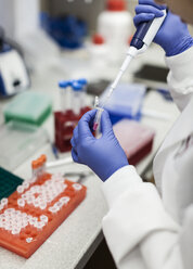 Scientist pouring chemical in vial through pipette at laboratory - FSIF01203