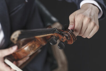 Ausgeschnittenes Bild eines Musikers, der Geigensaiten stimmt - FSIF01205
