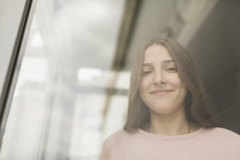 Low angle portrait of smiling teenage girl seen from window - FSIF01209