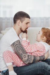 Seitenansicht eines Vaters, der mit seiner Tochter auf dem Sofa zu Hause spielt - FSIF01212
