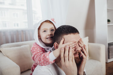 Tochter bedeckt die Augen des Vaters beim Spielen im Wohnzimmer zu Hause - FSIF01217