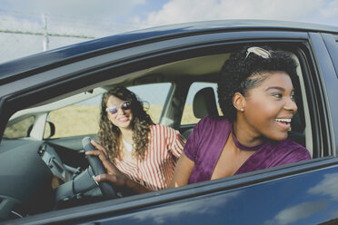 Lächelnde junge Frau schaut weg, während sie mit einer Freundin im Auto sitzt - FSIF01252