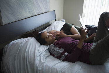 Hoher Blickwinkel des lesbischen Paares, das auf dem Bett liegt und ein digitales Tablet zu Hause benutzt - FSIF01258