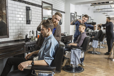 Hairdressers cutting male customer's hair in salon - FSIF01350