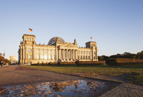 Deutschland, Berlin, Regierungsviertel, Reichstagsgebäude mit deutschen Fahnen im Herbst, Fernsehturm im Hintergrund - GWF05431