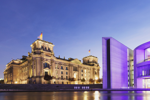 Germany, Berlin, Regierungsviertel, Reichstag building with German flags and Paul-Loebe-Building at Spree river in the evening stock photo