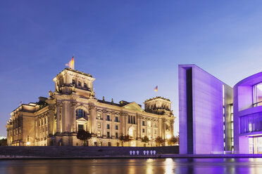 Germany, Berlin, Regierungsviertel, Reichstag building with German flags and Paul-Loebe-Building at Spree river in the evening - GWF05442