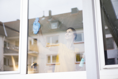 Smiling woman at home cleaning the window stock photo