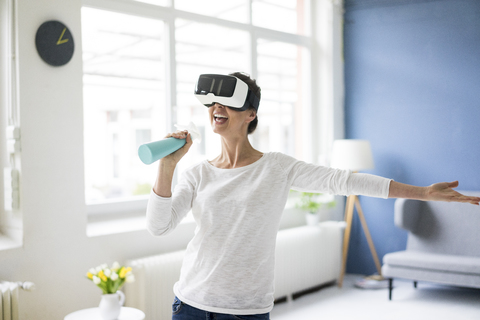 Vitale Frau beim Hausputz mit VR-Brille, lizenzfreies Stockfoto