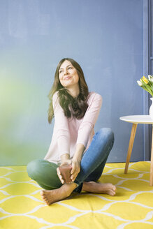 Lächelnde Frau sitzt auf dem Boden und hält ein Glas Saft - MOEF00814