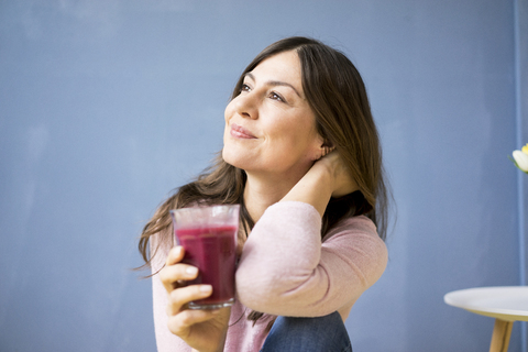 Lächelnde Frau hält ein Glas Saft, lizenzfreies Stockfoto