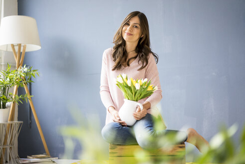 Porträt einer lächelnden Frau, die einen Strauß Tulpen in einem Gefäß hält - MOEF00829