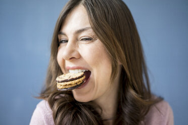 Porträt einer glücklichen Frau, die einen Kuchen isst - MOEF00832