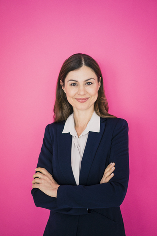 Porträt einer selbstbewussten Geschäftsfrau vor einer rosa Wand, lizenzfreies Stockfoto