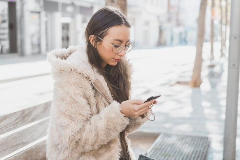 Stilvolle junge Frau in der Stadt, die ein Mobiltelefon benutzt - AFVF00019