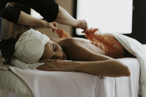 Junge Frau erhält eine Massage mit Federn in einem Spa - OCAF00146