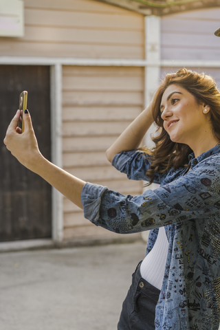 Lächelnde junge Frau nimmt Selfie mit Handy, lizenzfreies Stockfoto