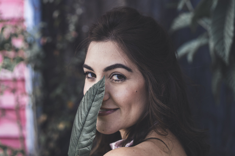 Porträt einer lächelnden jungen Frau mit Blatt, lizenzfreies Stockfoto