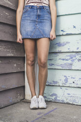 Young woman standing in a corner wearing denim skirt, partial view - AFVF00050