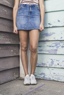 Junge Frau steht in einer Ecke und trägt einen Jeansrock, Teilansicht - AFVF00050