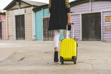 Rückenansicht einer gehenden Frau mit gelber Trolley-Tasche, Teilansicht - AFVF00058