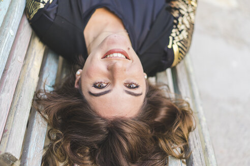 Porträt einer lachenden jungen Frau, die auf einer Bank liegt - AFVF00064