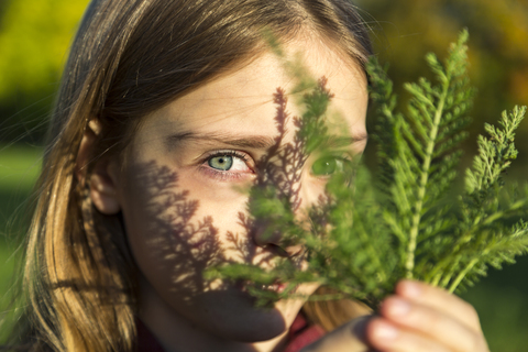 Portrait of girl with fern leaf at sunlight stock photo