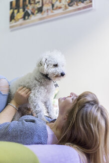 Junge Frau liegt auf dem Bett und spielt mit ihrem Hund - AFVF00071