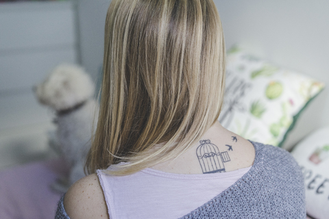 Rückenansicht einer blonden Frau mit Tätowierung am Hals, lizenzfreies Stockfoto