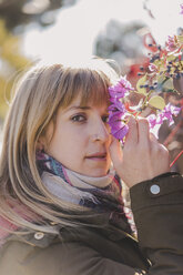 Porträt einer an Blumen riechenden Frau im Freien - AFVF00083