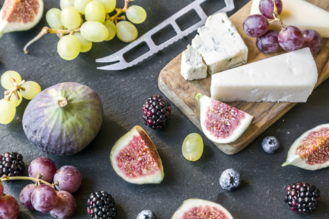 Plate with cheese, figs, grapes, blueberries, brambles, pecan, chopping board, knife stock photo