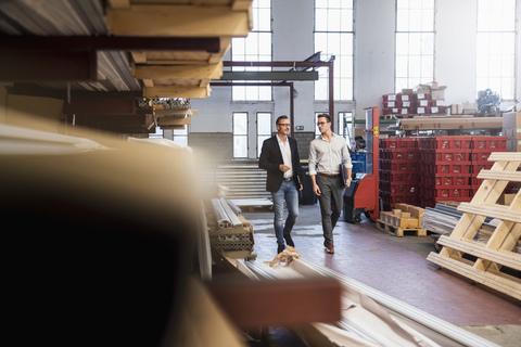 Zwei Geschäftsleute gehen in einem Lagerraum einer Fabrik, lizenzfreies Stockfoto