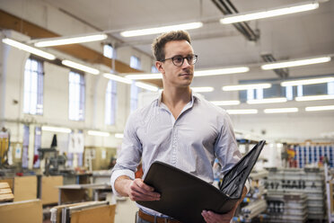 Young businessman in factory holding folder - DIGF03342