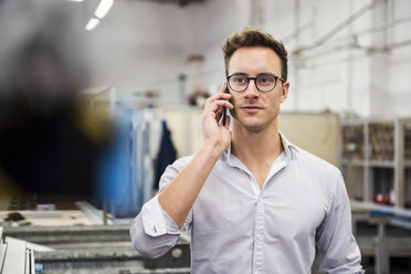 Young businessman on cell phone in factory - DIGF03345