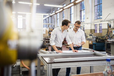 Zwei Geschäftsleute in einer Fabrik besprechen einen Plan - DIGF03349