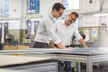 Two smiling businessmen in factory looking at plan - DIGF03351