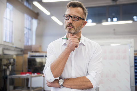 Mature businessman in factory thinking stock photo