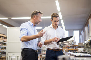 Zwei Geschäftsleute diskutieren in einer Fabrik über ein Produkt - DIGF03361