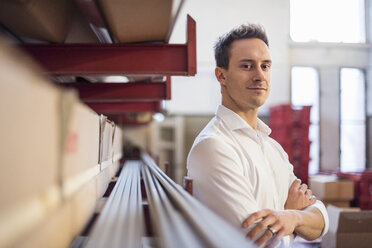 Portrait of confident young businessman in factory storeroom - DIGF03371