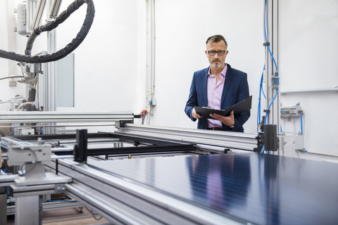 Mature businessman in solar factory holding folder stock photo