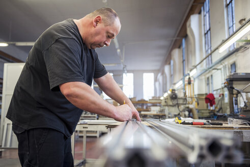 Mann in Fabrik bei der Arbeit an einem Metallteil - DIGF03382