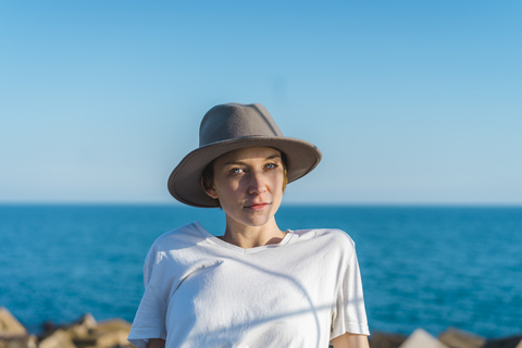 Porträt einer Frau mit Hut vor dem Meer, lizenzfreies Stockfoto