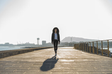 Spanien, Barcelona, Frau mit Kapuzenjacke auf der Promenade - AFVF00113