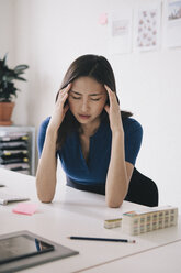 Junge Geschäftsfrau mit Kopfschmerzen am Schreibtisch - FSIF01374