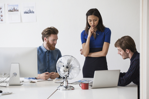 Junge Geschäftsleute, die am Schreibtisch diskutieren, lizenzfreies Stockfoto