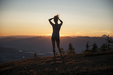 Rückansicht einer Frau in voller Länge, die bei Sonnenaufgang auf einem Berg steht - FSIF01385